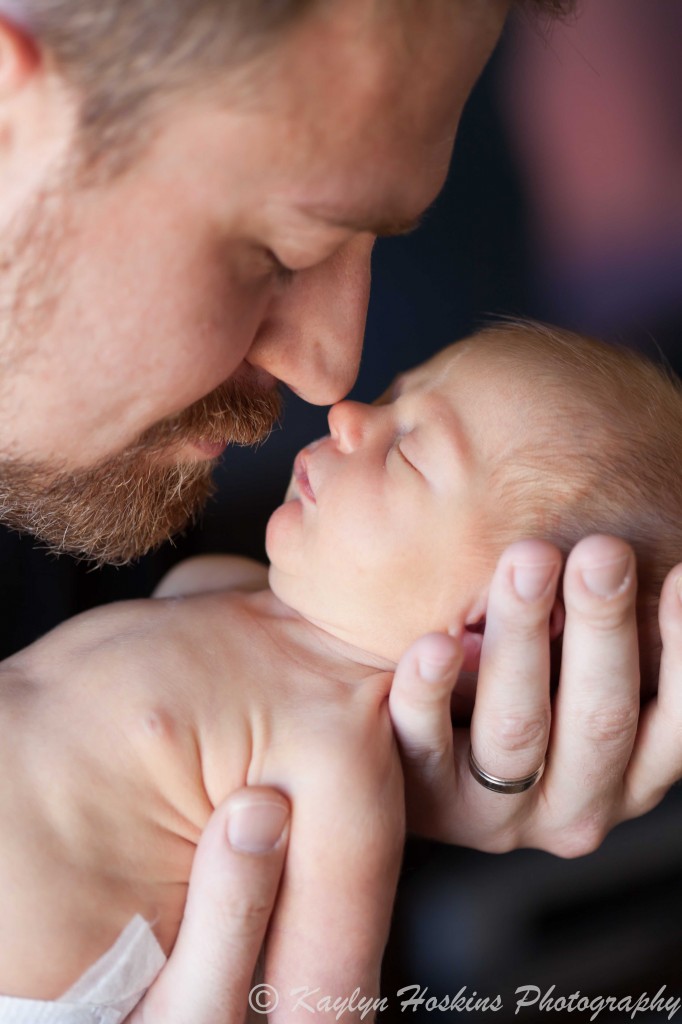 brand new dad rubbing noses with sleeping newborn boy