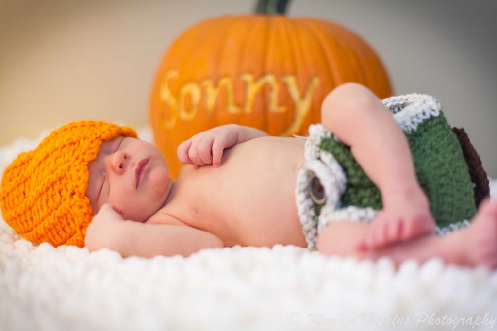 newborn Sonny sleeping in front of pumpkin in which his name is carved