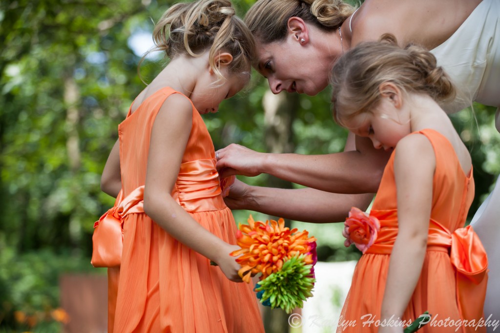 Bride helps little bridesmaid fix her dress before the ceremony 