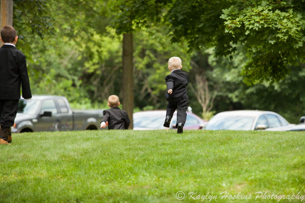 Little ring bearer runs around outside church before wedding at The Little Brown Church in Nashua, IA 