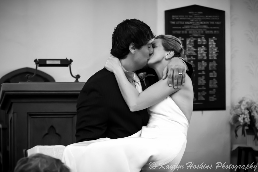 Groom picks up bride for a spectacular kiss at the Little Brown Church in Nashua