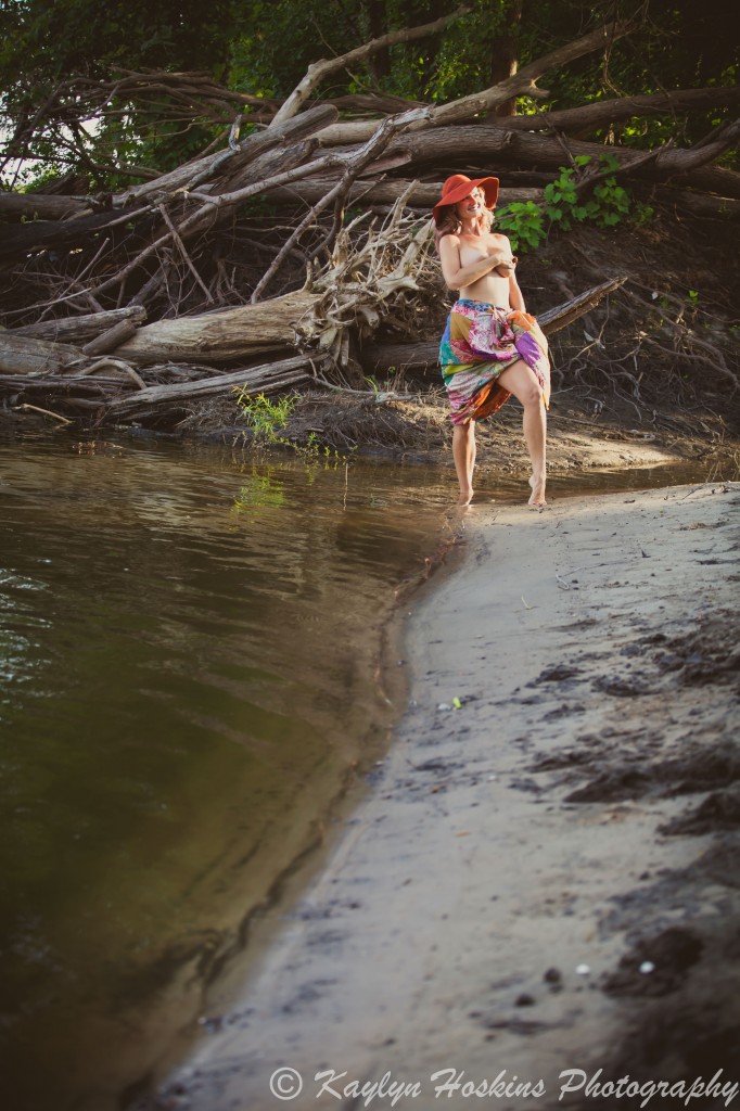 Gorgeous Woman standing by water in just hat and skirt