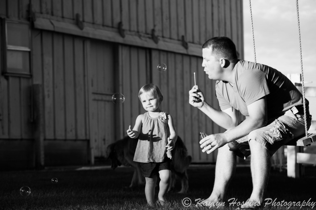 Dad blows bubbles for daughter to catch during family photos